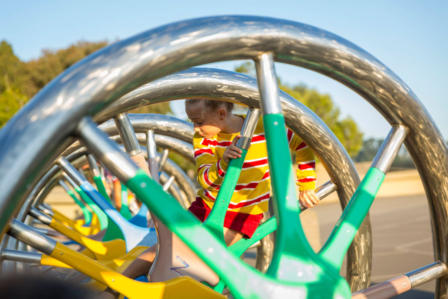 A young person climbing on the DNA Sculpture on the plaza at The Lawrence