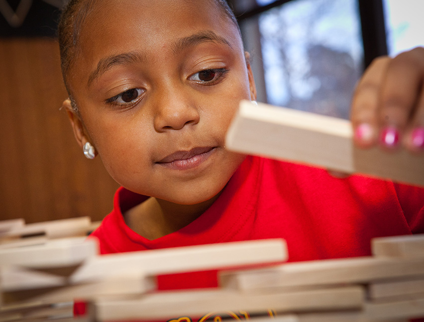 A child building with KEVA planks